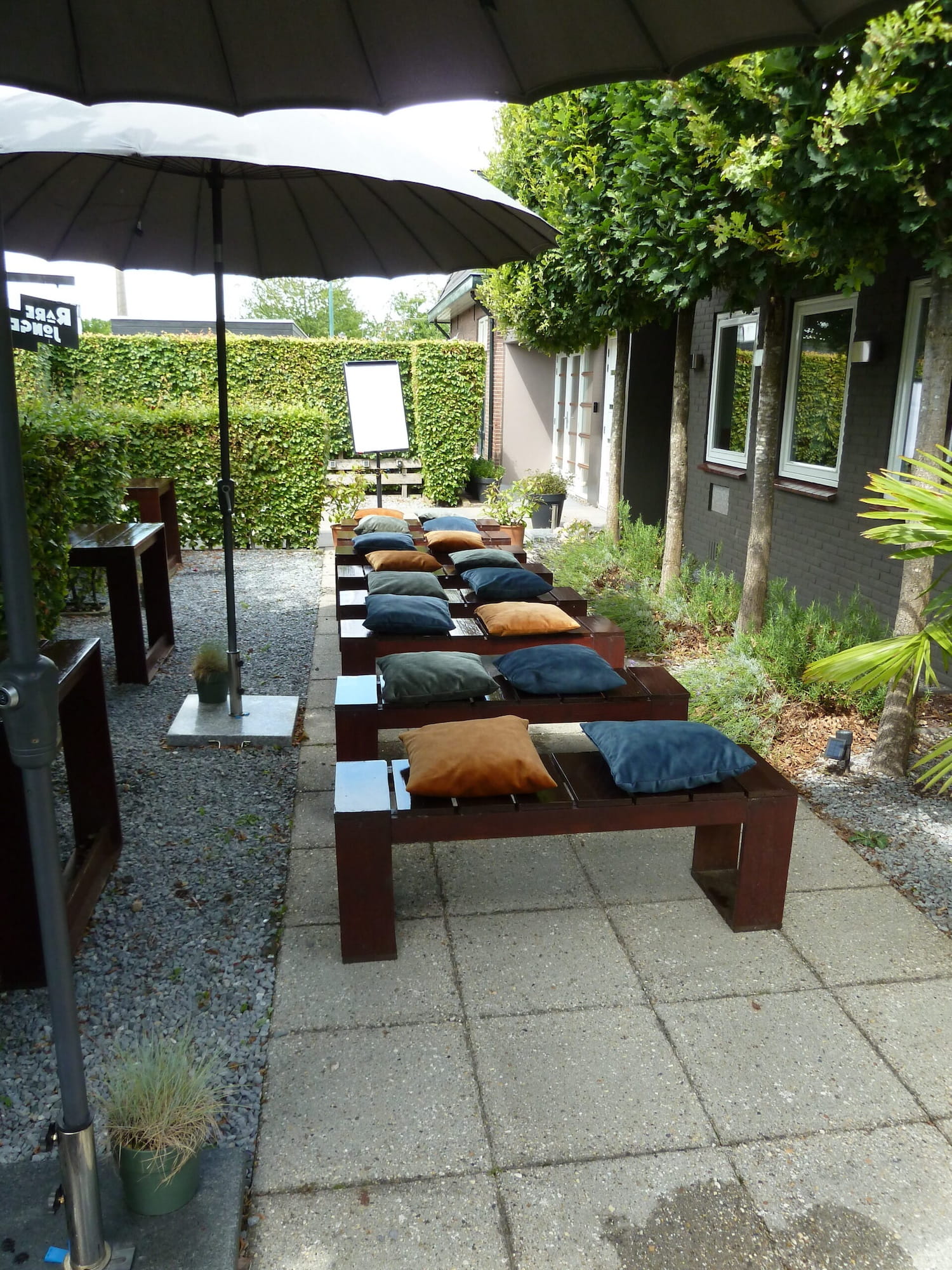 Als het zonnetje even schijnt dan kun je op het terras zitten, hier een voorbeeld van acht houten banken met zachte kussens